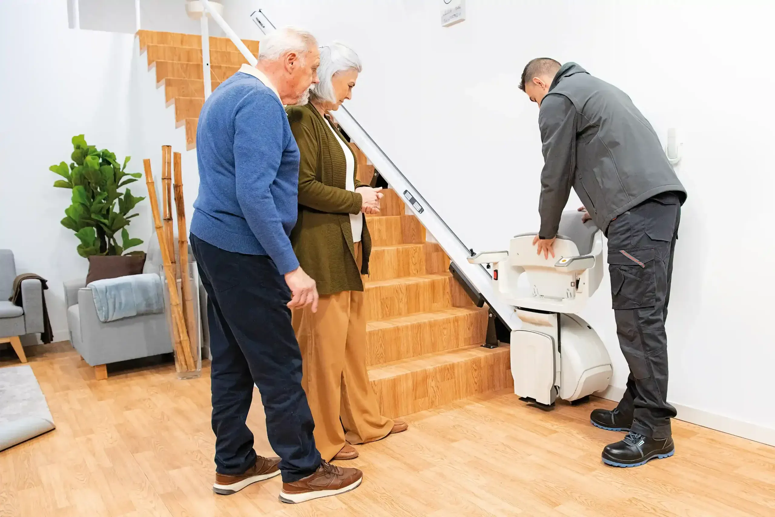 Técnico mostrando el funcionamiento de una silla salvaescaleras a una pareja mayor