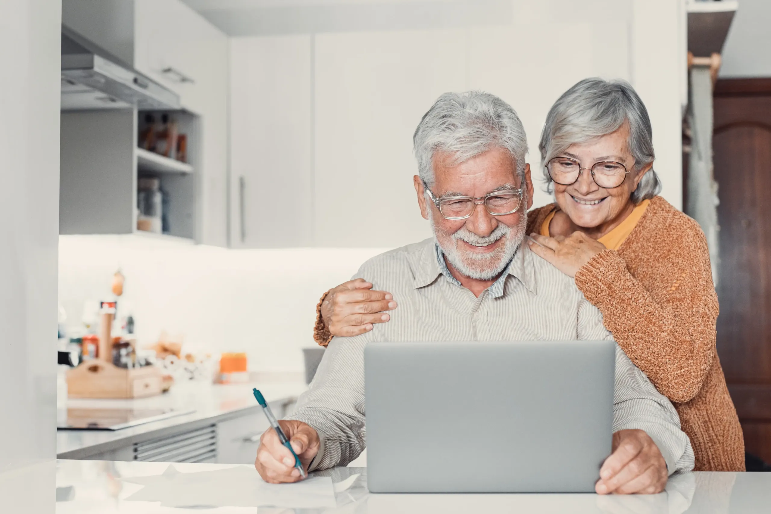Pareja mayor sonriente consultando información en un portátil